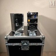 two speakers sitting on top of a case on a table
