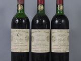 three bottles of red wine sit on a glass table