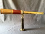 un télescope ancien en laiton muni d'une poignée en bois, sur fond gris