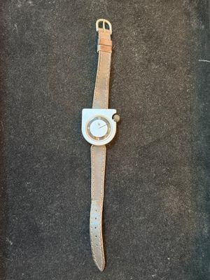 watch on a black surface with a brown strap and a white face