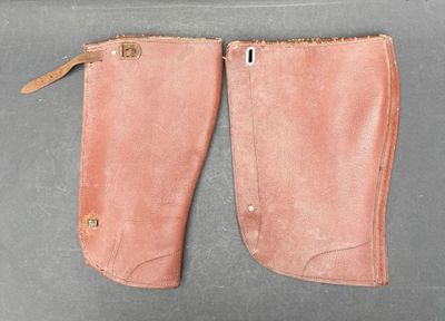 une paire de bottes d'équitation en cuir rose posées sur une surface grise