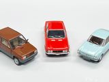 trois petites voitures miniatures posées les unes à côté des autres sur une surface blanche