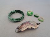 two pieces of jewelry sitting on a table next to each other