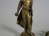 a bronze statue of a man standing next to a small statue of a man