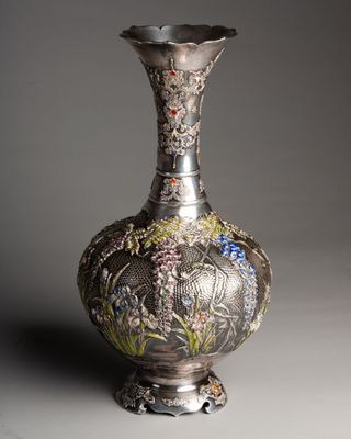 a silver vase with a floral design on it