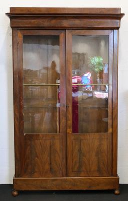 une armoire en bois avec une porte vitrée et une horloge posée dessus