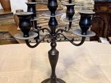 a black candelab with five candles on it on a table