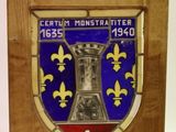 plaque en bois ornée d'un blason bleu et jaune et d'un drapeau rouge et blanc