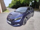 the blue nissan leaf is parked on the side of the road