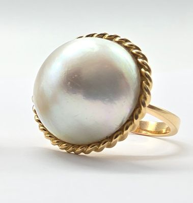 une photo d'une bague ornée d'une perle blanche