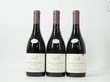 trois bouteilles de vin sont alignées sur une surface blanche