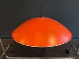 an orange lamp hanging from a metal frame on a gray wall
