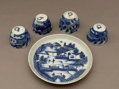 une assiette bleue et blanche sur laquelle sont posés quatre salières et poivrières