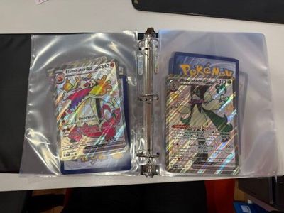 deux cartes Pokémon dans un classeur posé sur une table