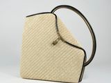 a beige and black handbag with a black handle on a white background
