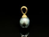 un gros plan d'un pendentif en perle sur une surface noire