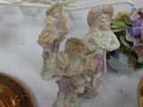 some figurines are sitting on a table next to a basket of flowers