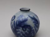 a blue and white vase with a black lid on a white surface
