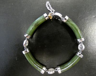 bracelet composé de perles de jade vert et d'argent sur un fond noir