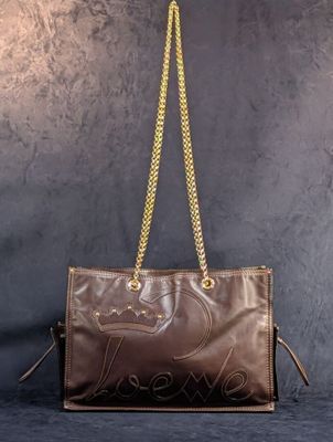 un sac à main en cuir marron auquel est suspendue une chaîne dorée