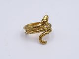 a close up of a gold snake ring on a white surface