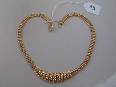a close up of a gold necklace on a white surface