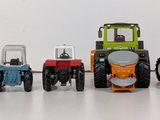 several toy tractors are lined up in a row on a white surface
