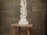 a white sculpture sitting on a small table in front of a brick wall