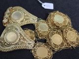 plusieurs bijoux en or posés sur un fond noir, accompagnés d'une étiquette de prix