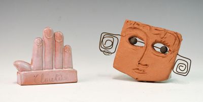 deux figurines en argile représentant un visage et une main