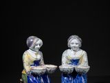 two figurines of two women sitting on a black surface