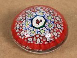une boule en verre rouge ornée de fleurs blanches et bleues