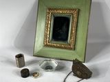 une photo représentant un cadre, une image, un couteau et d'autres objets posés sur une surface blanche