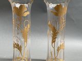 pair of gold and clear vases with flowers and leaves on them