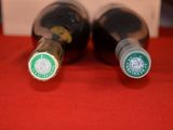 two bottles of wine sitting on a red table