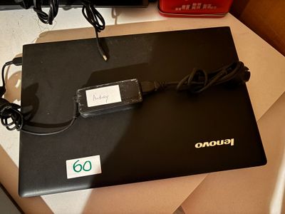 un ordinateur portable noir posé sur un bureau, avec son chargeur