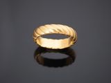 une bague en or au motif torsadé sur un fond noir