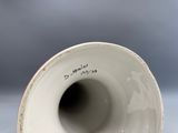 un vase blanc orné d'une inscription, posé sur une table