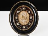 a black and gold plate with a face on it