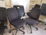 Quatre chaises de bureau sont alignées en rang dans une pièce