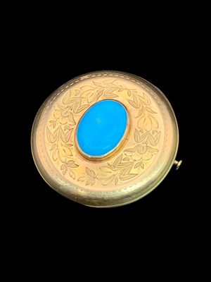 une pierre turquoise dans un écrin plaqué or sur fond noir