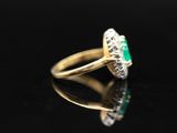 an emerald and diamond ring on a black surface
