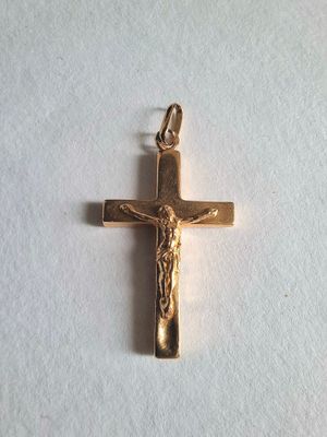 a gold cross with jesus on it on a white surface