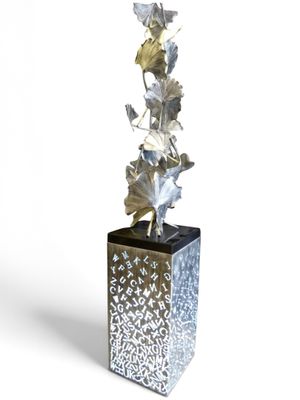a silver vase with a plant in it on a white background