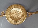 a close up of a gold coin on a chain on a table