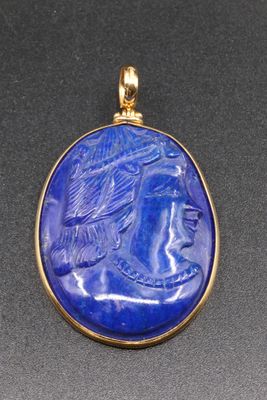 a gold and lapis pendant with an image of a woman wearing a headdress