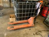 un grand conteneur noir posé sur une palette dans un garage