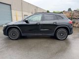 a black mercedes suv parked in a parking lot next to a pile of wood