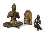 trois figurines en bronze représentant un homme et une femme assis sur un rocher