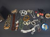 many different necklaces and bracelets laid out on a table